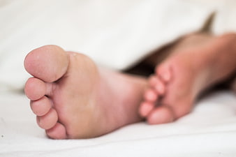 Close-up of bare feet resting on white bedding