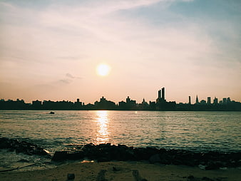 Sunset Silhouette of City Skyline Over Water and Beach