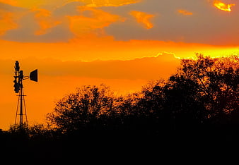 Silhouette of windmill against vibrant orange sunset sky