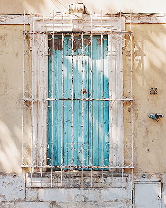 Vintage turquoise window with white iron bars on old wall