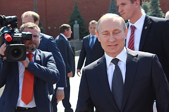 Vladimir Putin walking outdoors with press and security