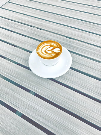 Top view of latte art coffee on white wooden table