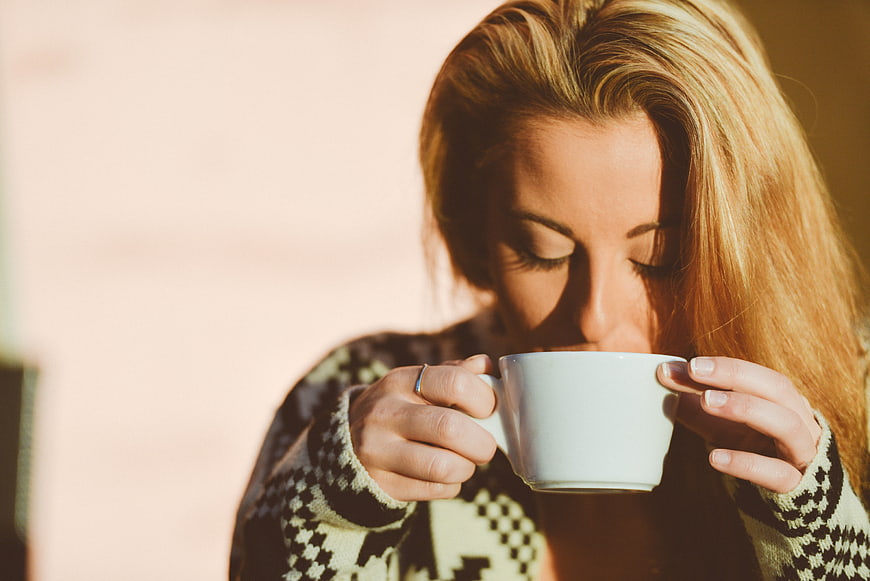 Blonde Woman Sipping Coffee in Patterned Sweater