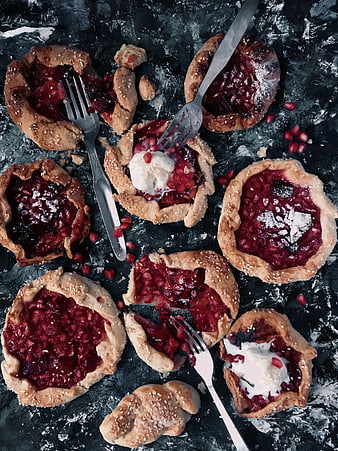 Mini plum pomegranate galettes with cream on dark background