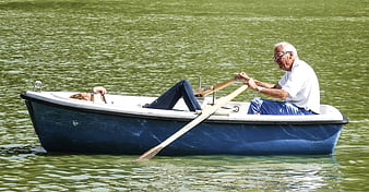 Senior couple rowing a blue boat on a green lake