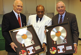 Three Men Holding Framed Platinum Records in Office