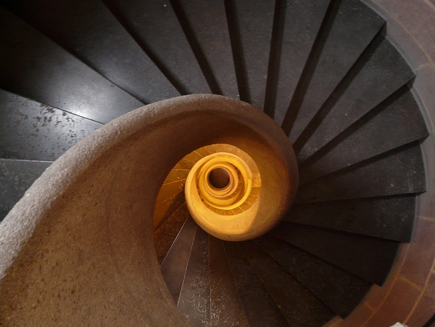 Top-down view of a dark stone spiral staircase
