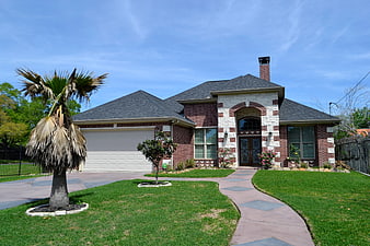Brick suburban home with palm tree and green lawn