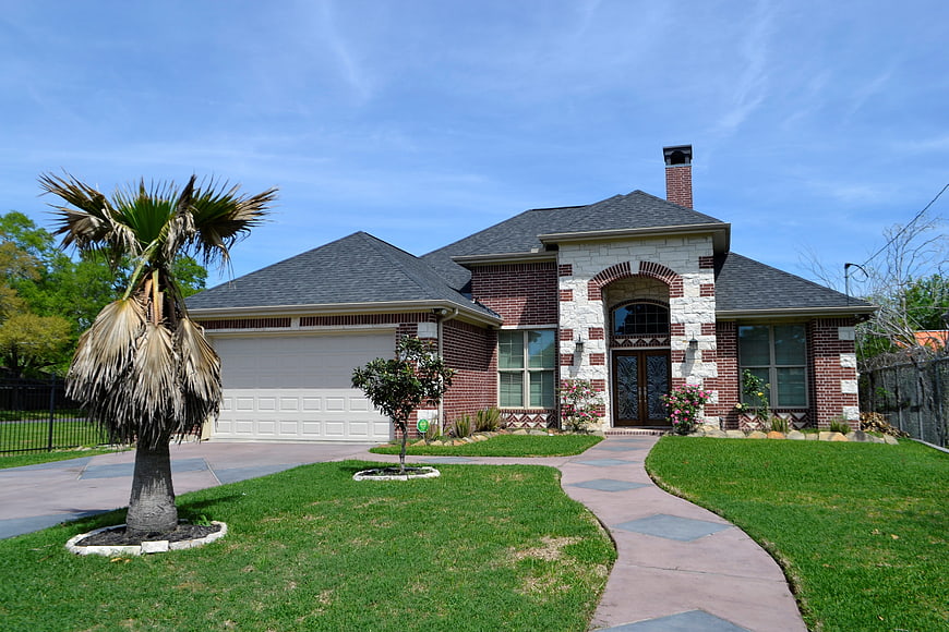 Brick suburban home with palm tree and green lawn