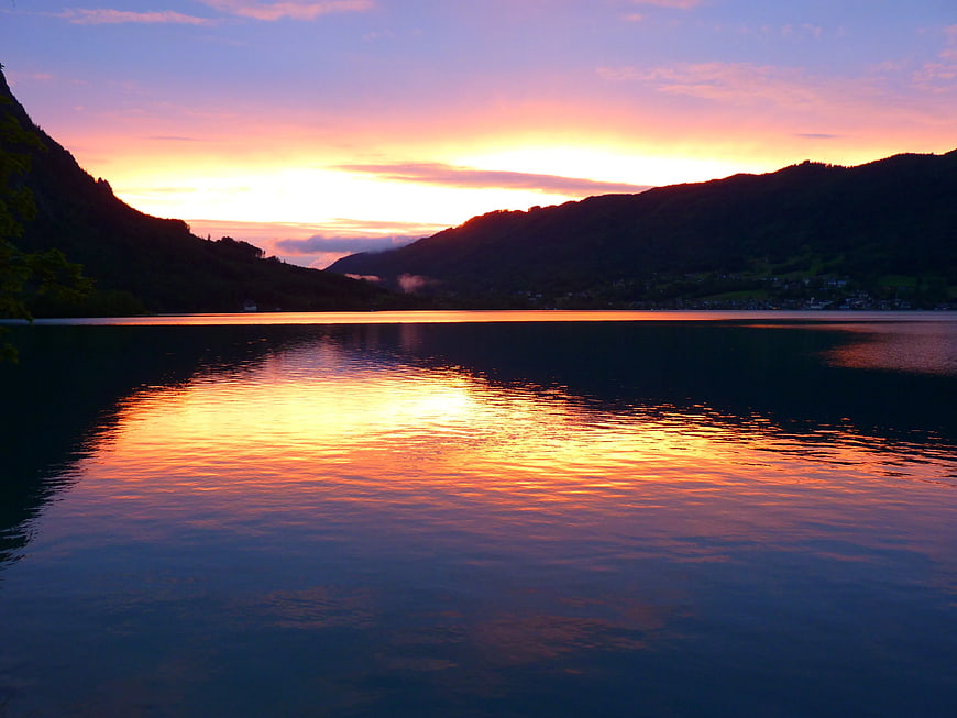Serene sunset reflection on calm lake surrounded by mountains