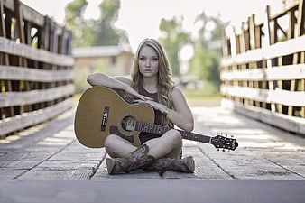 Young Woman with Acoustic Guitar on Wooden Bridge