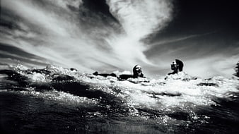 Dramatic black and white photo of people swimming in ocean waves
