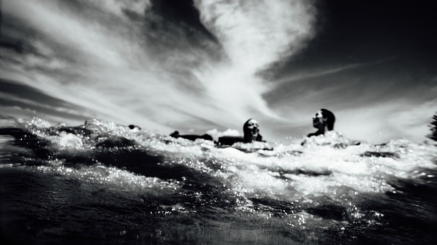 Dramatic black and white photo of people swimming in ocean waves