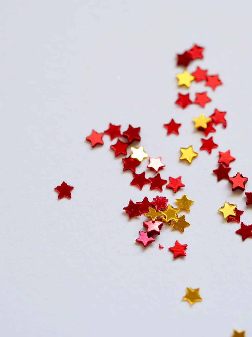 Red and Gold Star Confetti on White Background