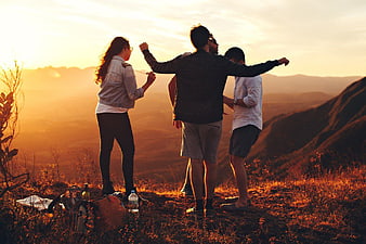 Friends Celebrating on Mountain Peak at Sunset