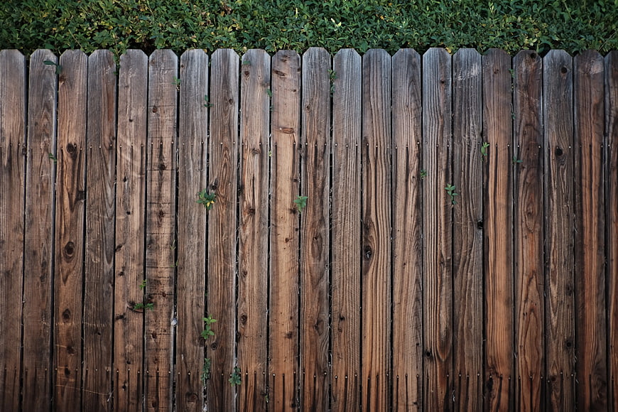 Weathered Wooden Fence Texture with Green Foliage Background