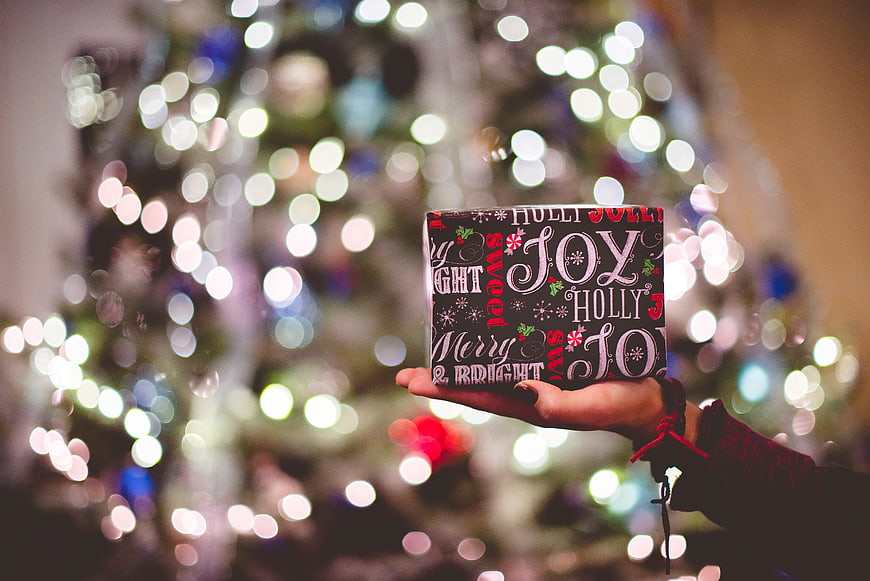 Hand holding Christmas gift box with bokeh lights background