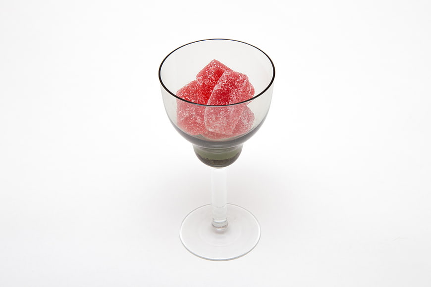 Red Sugar-Coated Candies in a Glass on White Background