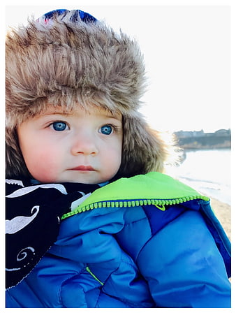 Cute toddler in winter hat and blue jacket outdoors