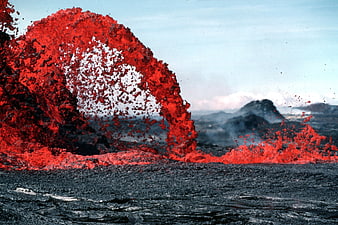 Dramatic volcanic lava fountain erupting against blue sky