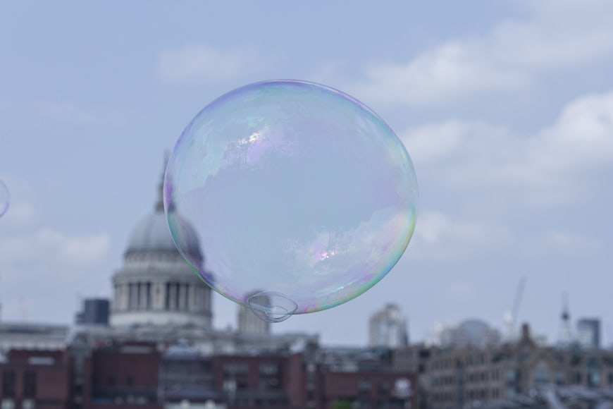 Iridescent soap bubble floating over London cityscape