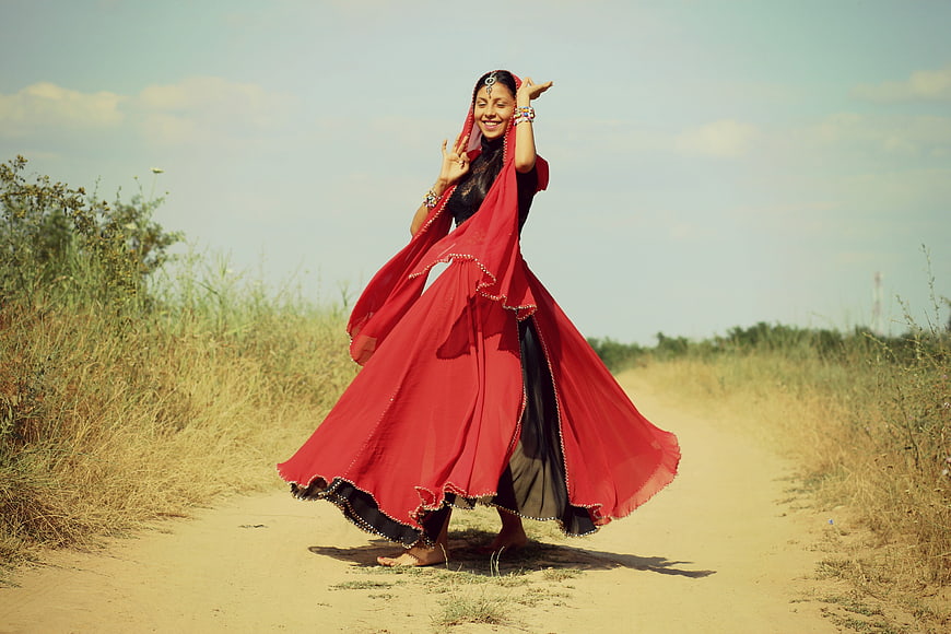 Woman in red traditional dress dancing on dirt road
