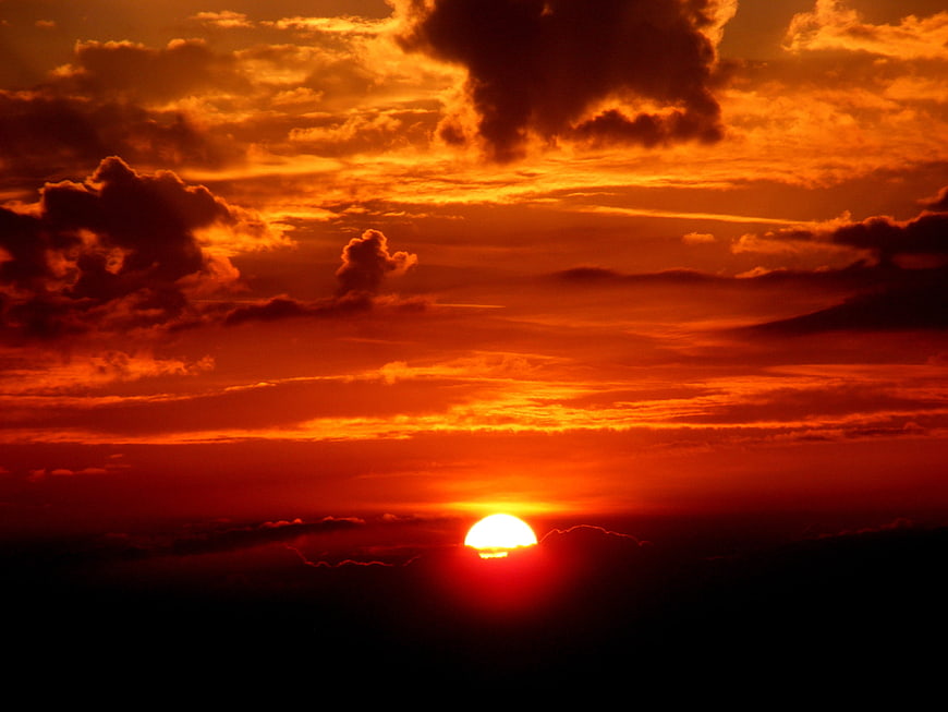 Dramatic fiery orange sunset with clouds and glowing sun