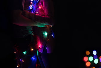 Couple wrapped in colorful Christmas lights at night