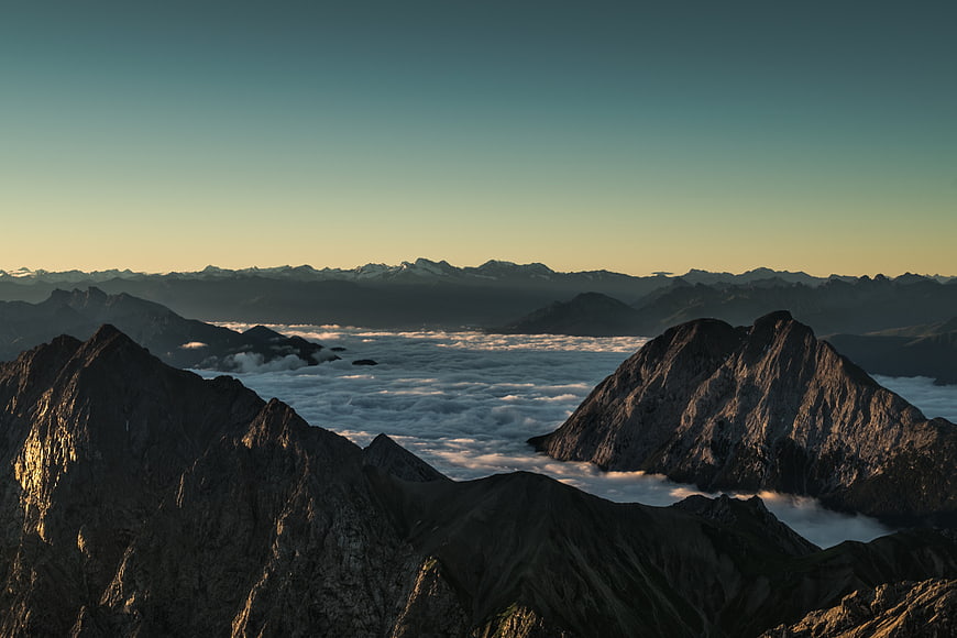 Majestic Mountain Peaks Above Sea of Clouds at Sunset