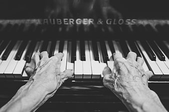 Senior hands playing piano keys in black and white