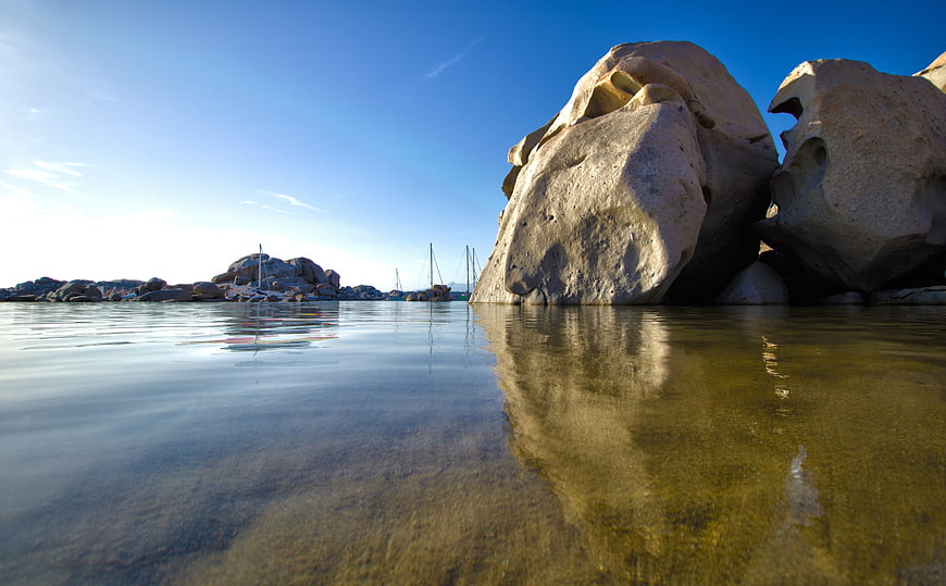 Low angle view of large granite boulders in calm sea water