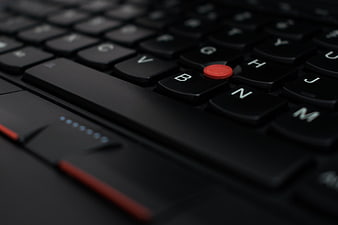 Close-up of a black laptop keyboard with a red trackpoint button