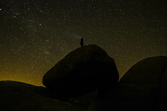 Silhouette of person stargazing on rock under Milky Way