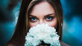 Close-up portrait of woman with blue eyes holding white flower