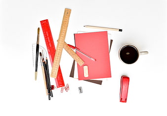 Flat lay of red stationery, rulers, and coffee on white background