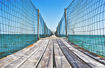 Wooden pier with safety netting over turquoise ocean