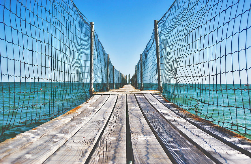 Wooden pier with safety netting over turquoise ocean
