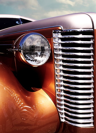 Close-up of vintage car headlight and chrome grille
