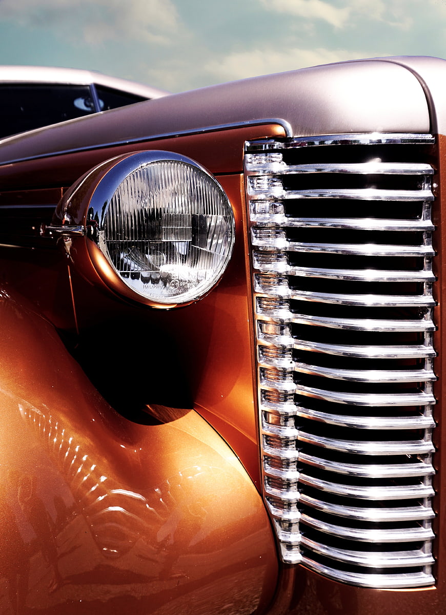 Close-up of vintage car headlight and chrome grille