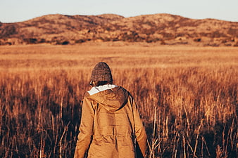 Person in Beanie and Jacket Walking Through Golden Field