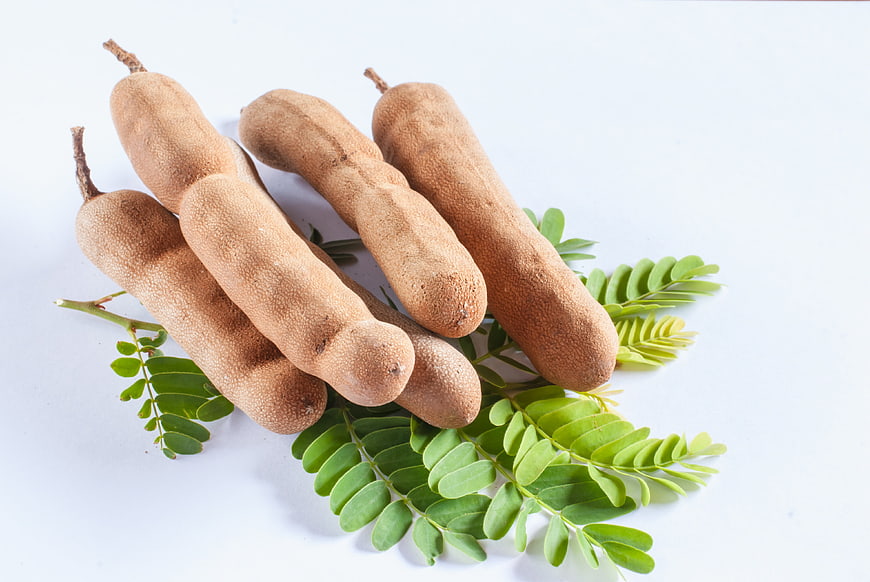 Fresh Tamarind Pods With Green Leaves On White Background