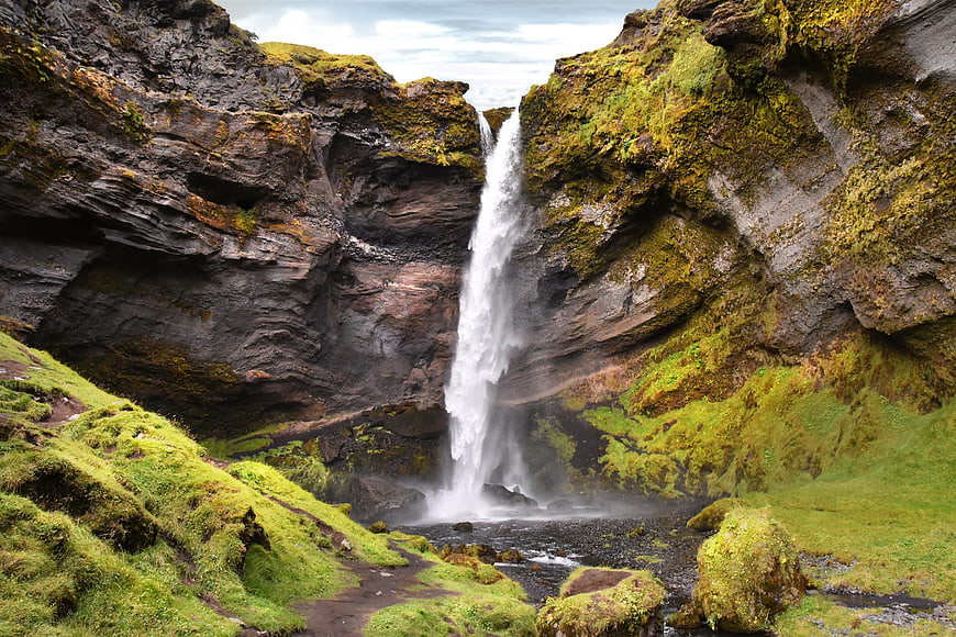 Mossy waterfall cascading into a rocky pool in Iceland