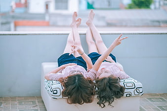 Two women relaxing on rooftop with peace signs