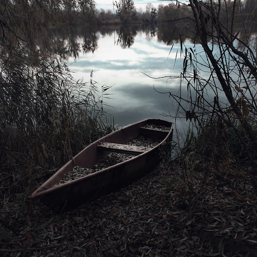 Abandoned rusty boat on riverbank in autumn