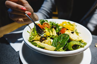 Close-up of fresh salad with olives and tomatoes in white bowl
