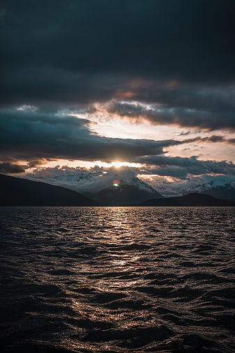 Dramatic Sunset Over Mountain Lake with Golden Reflections