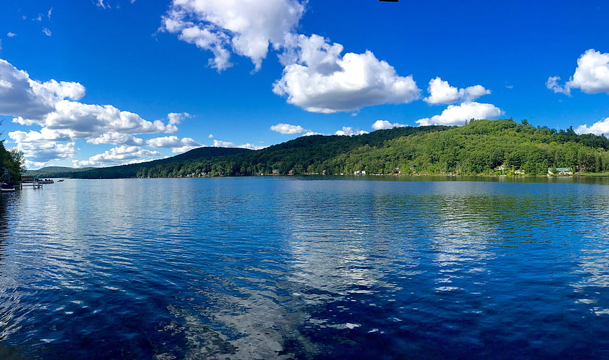 Panoramic View of Serene Lake with Blue Sky and Green Hills