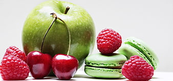 Fresh Green Apple, Cherries, Raspberries, and Macarons on White Background