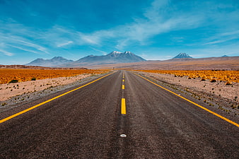 Straight Desert Highway Leading to Snow-Capped Volcanoes