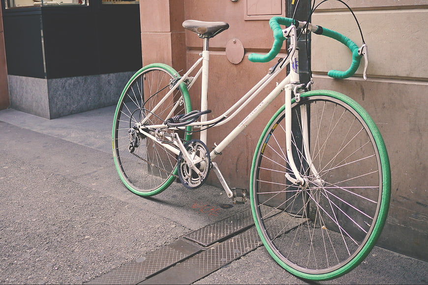 Vintage White Bicycle with Green Tires Parked on Street